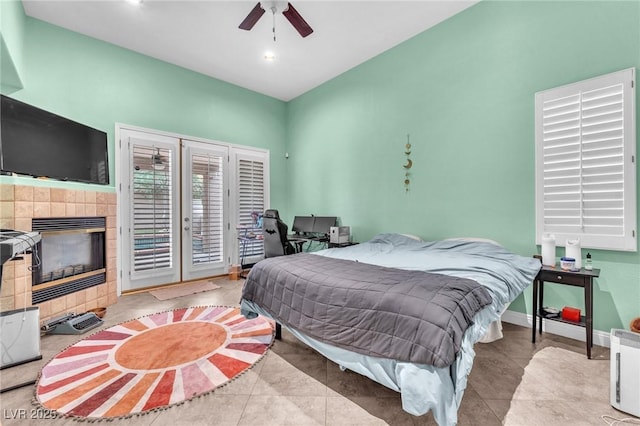 tiled bedroom featuring access to exterior, a fireplace, baseboards, and ceiling fan