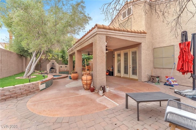 view of patio with ceiling fan, an outdoor hot tub, and a fenced backyard