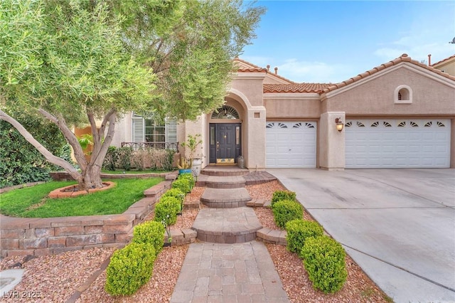 mediterranean / spanish-style home with a tiled roof, stucco siding, driveway, and an attached garage