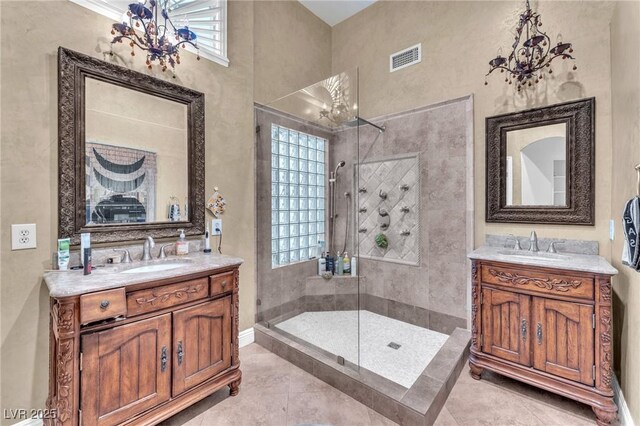 full bath with a tile shower, two vanities, and a sink