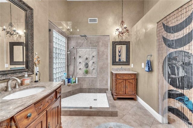 full bath with two vanities, a walk in shower, a chandelier, and a sink