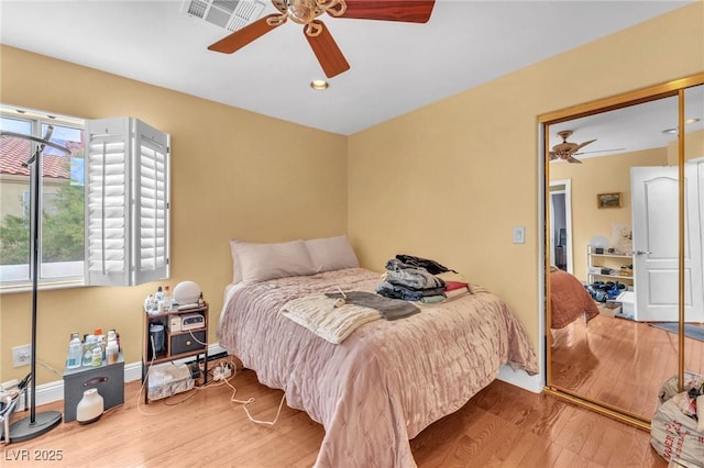 bedroom with visible vents, baseboards, a ceiling fan, and wood finished floors