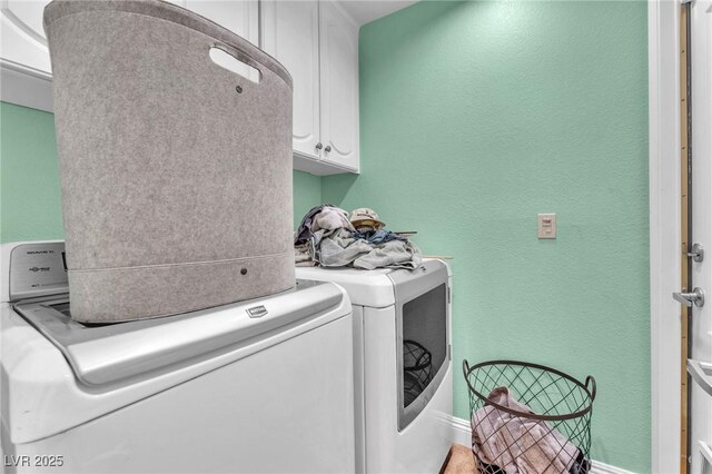 laundry room featuring baseboards, cabinet space, washing machine and dryer, and a textured wall