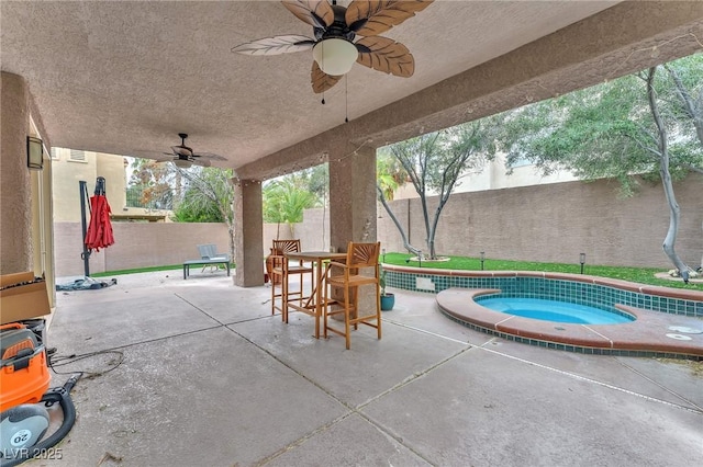 view of patio with a ceiling fan, an in ground hot tub, outdoor dining area, and a fenced backyard