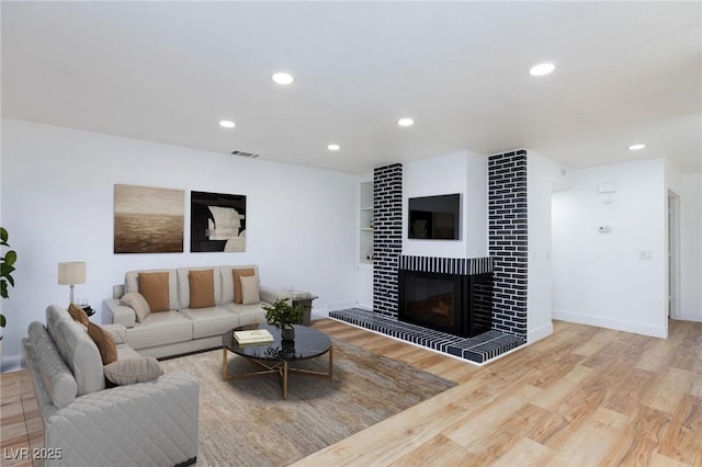 living room with visible vents, baseboards, recessed lighting, a fireplace, and wood finished floors