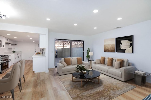 living area featuring light wood-type flooring, visible vents, baseboards, and recessed lighting