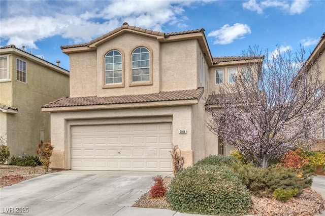 mediterranean / spanish house featuring stucco siding, driveway, an attached garage, and a tiled roof