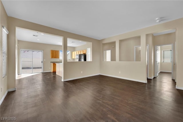 unfurnished living room featuring visible vents, baseboards, and dark wood finished floors