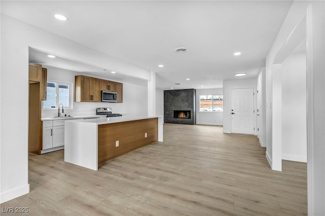 kitchen featuring stainless steel appliances, light countertops, open floor plan, white cabinets, and a sink