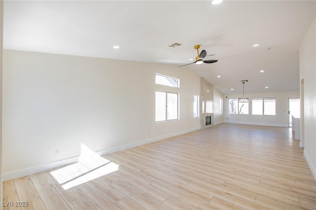 unfurnished living room featuring light wood finished floors, ceiling fan, baseboards, and vaulted ceiling