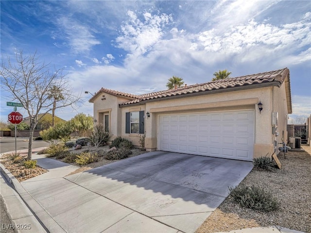 mediterranean / spanish house featuring driveway, an attached garage, a tile roof, and stucco siding