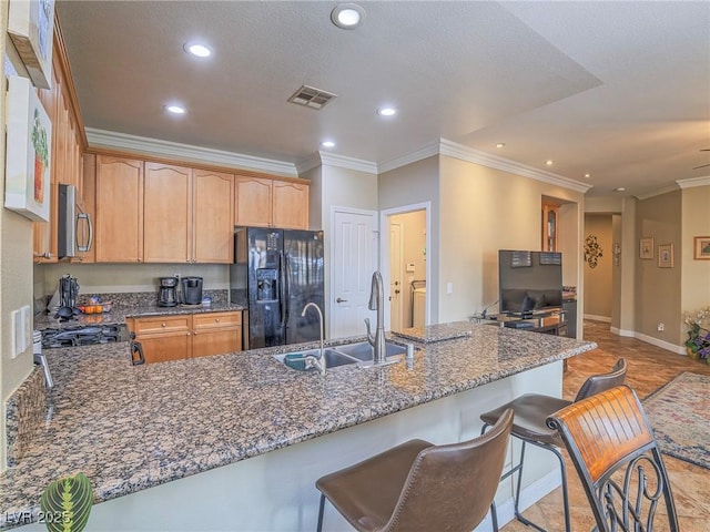 kitchen with stainless steel microwave, a peninsula, black fridge, a sink, and recessed lighting