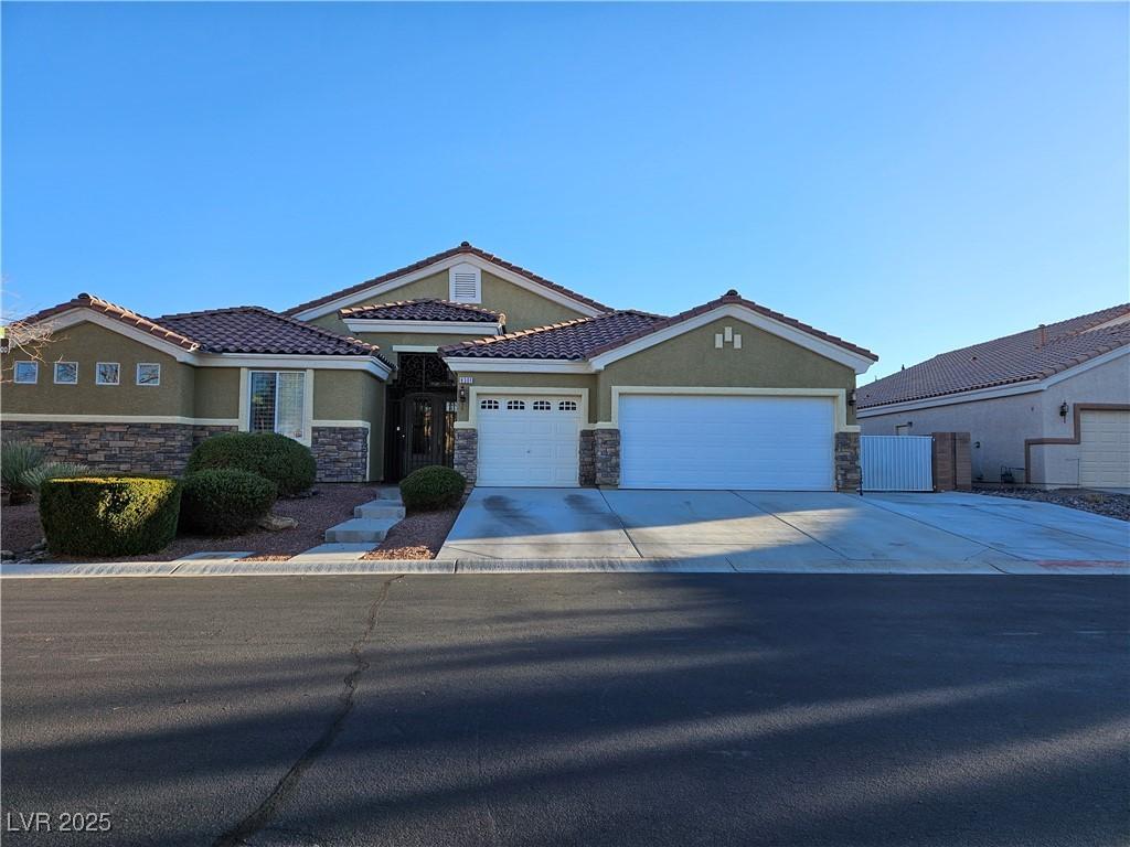 view of front facade featuring stone siding, concrete driveway, and stucco siding