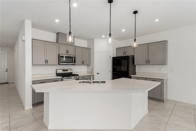 kitchen with appliances with stainless steel finishes, light countertops, hanging light fixtures, and an island with sink