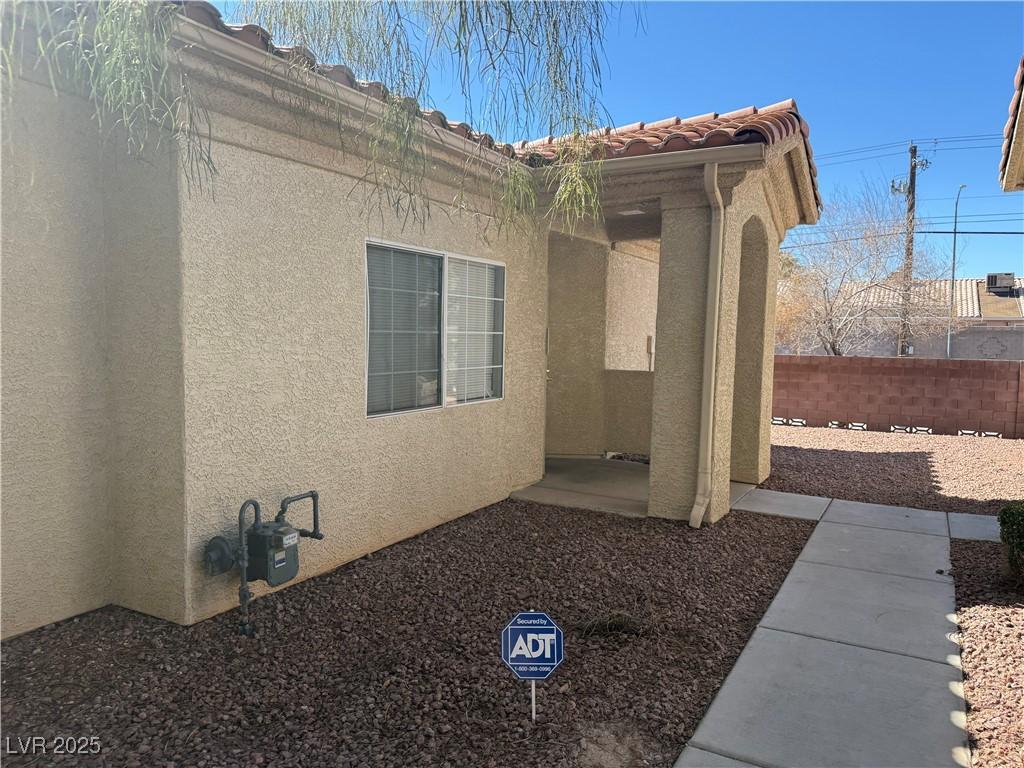 view of property exterior with a tiled roof, fence, and stucco siding