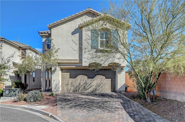 view of front of property featuring decorative driveway, a tile roof, an attached garage, and stucco siding