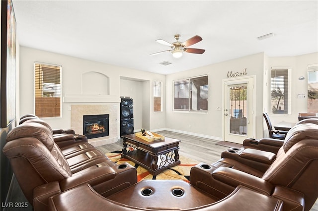 living area with light wood finished floors, ceiling fan, visible vents, and a tiled fireplace