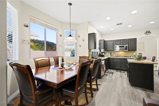 dining space with arched walkways, recessed lighting, visible vents, baseboards, and light wood-style floors