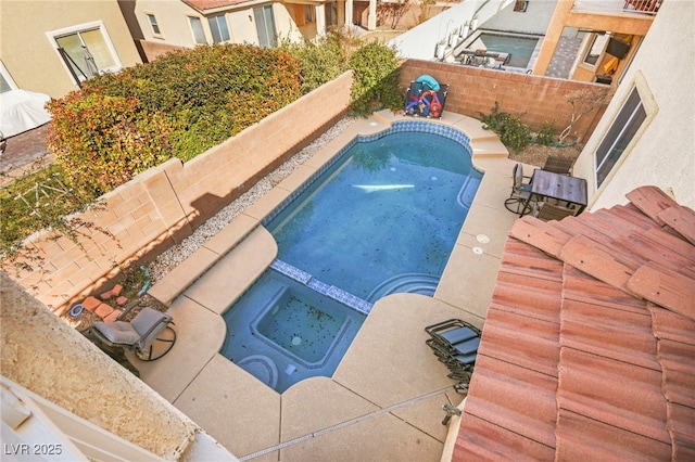 view of swimming pool featuring a fenced backyard and a pool with connected hot tub