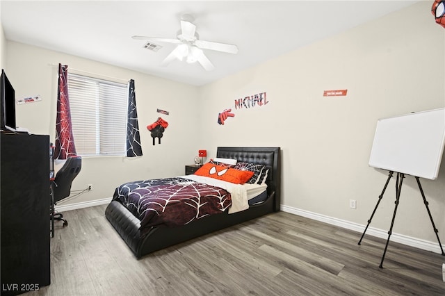 bedroom with ceiling fan, wood finished floors, visible vents, and baseboards