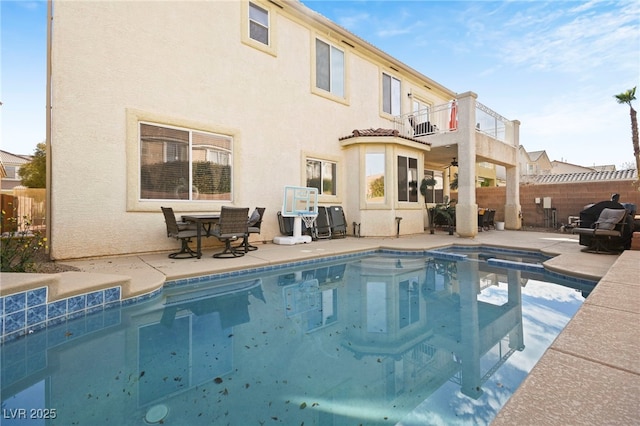 rear view of house with a patio area, fence, a balcony, and stucco siding