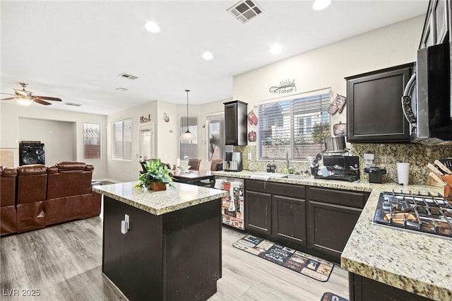 kitchen featuring a center island, visible vents, hanging light fixtures, appliances with stainless steel finishes, and open floor plan