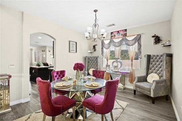 dining space featuring a chandelier, arched walkways, visible vents, and wood finished floors