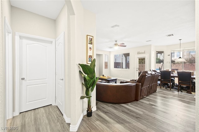 living area featuring ceiling fan, wood finished floors, visible vents, and baseboards