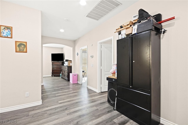 interior space with arched walkways, light wood finished floors, light countertops, visible vents, and baseboards