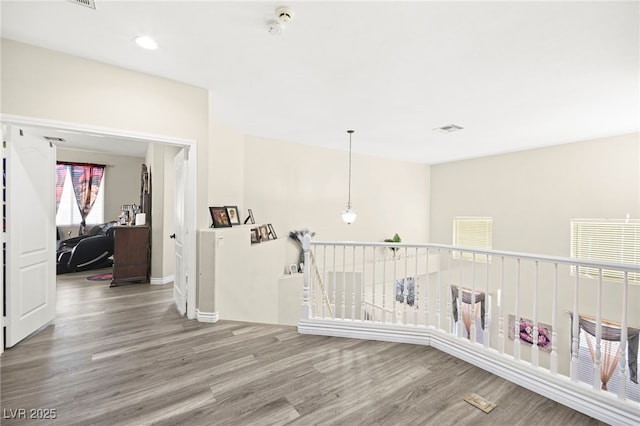 corridor featuring visible vents, an upstairs landing, and wood finished floors