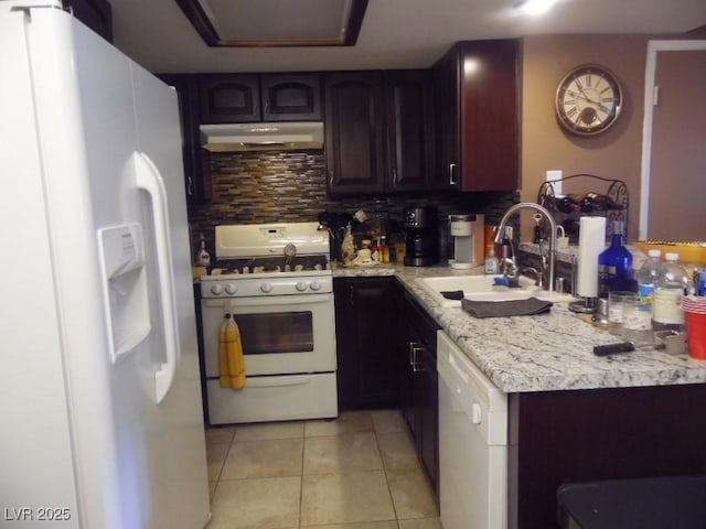 kitchen featuring light tile patterned floors, under cabinet range hood, white appliances, a sink, and decorative backsplash