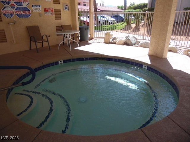 view of swimming pool with a hot tub and fence