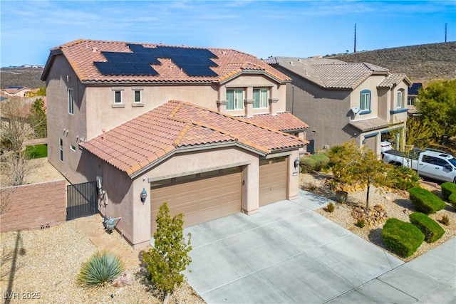 mediterranean / spanish-style house with stucco siding, concrete driveway, a gate, a garage, and a tiled roof