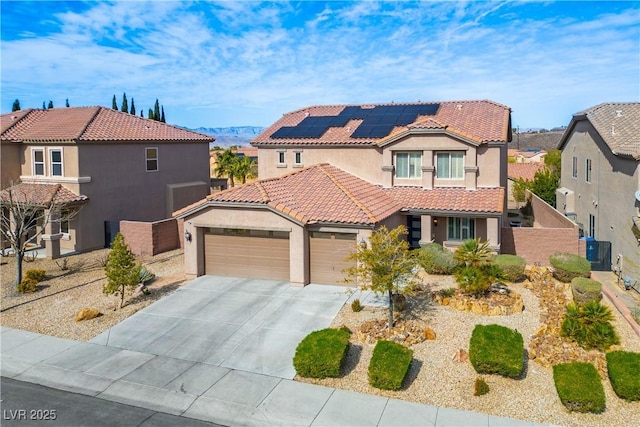 mediterranean / spanish house featuring a garage, solar panels, a tiled roof, concrete driveway, and stucco siding