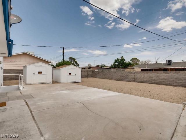 view of patio featuring a fenced backyard, an outdoor structure, and a storage shed