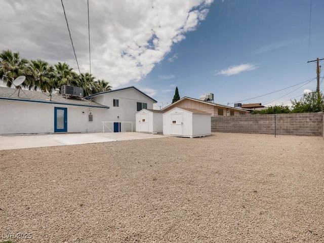 back of house with a storage shed, central AC unit, an outdoor structure, and a fenced backyard