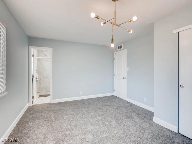 unfurnished bedroom featuring baseboards, visible vents, ensuite bathroom, an inviting chandelier, and carpet floors