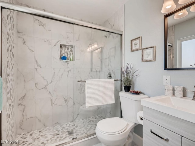 bathroom featuring a marble finish shower, vanity, and toilet