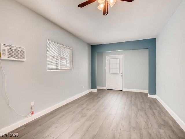 unfurnished room with a wall unit AC, ceiling fan, baseboards, and wood finished floors