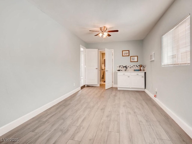 interior space featuring a ceiling fan, light wood-type flooring, and baseboards