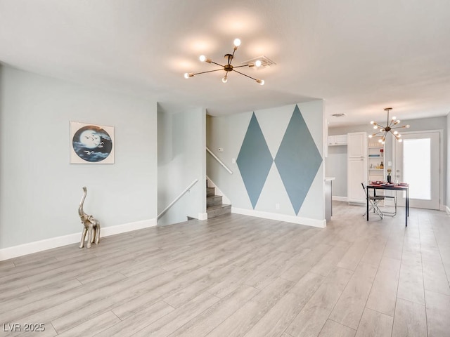 unfurnished living room featuring baseboards, stairway, light wood-style flooring, and a notable chandelier