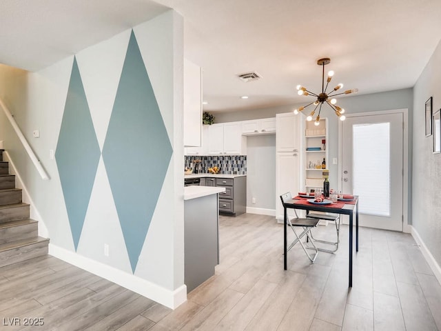 kitchen with visible vents, baseboards, white cabinetry, light countertops, and tasteful backsplash