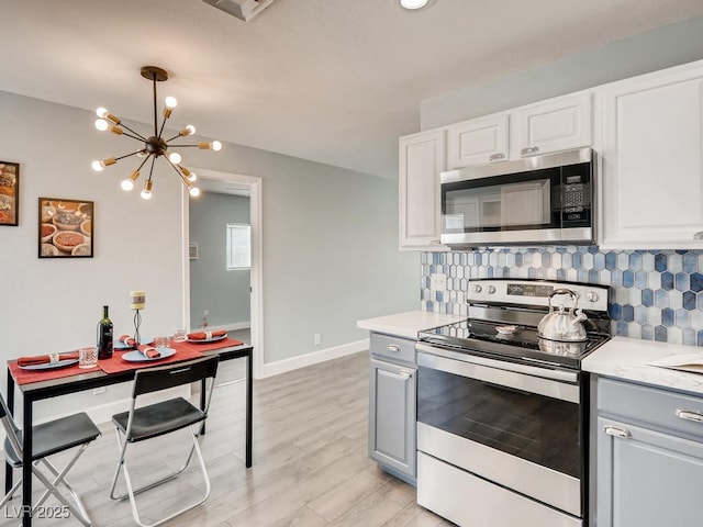 kitchen featuring light wood-style flooring, appliances with stainless steel finishes, light countertops, and backsplash