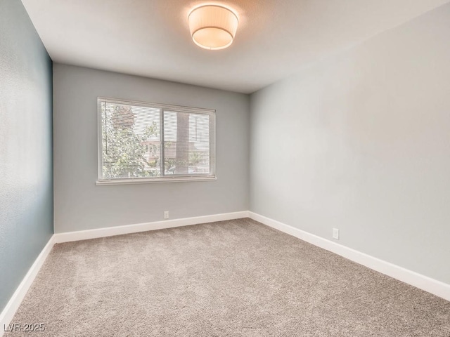 carpeted empty room featuring baseboards