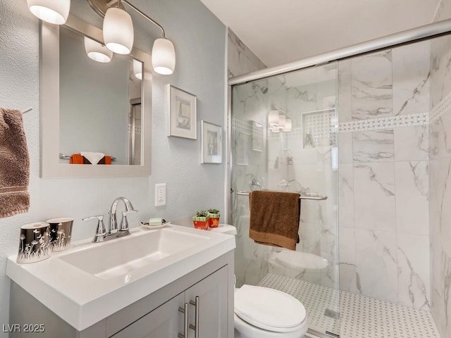 bathroom featuring toilet, a textured wall, a marble finish shower, and vanity