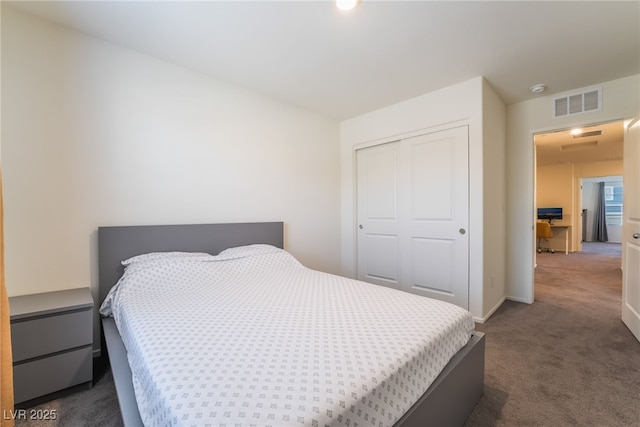 bedroom with baseboards, visible vents, dark colored carpet, and a closet