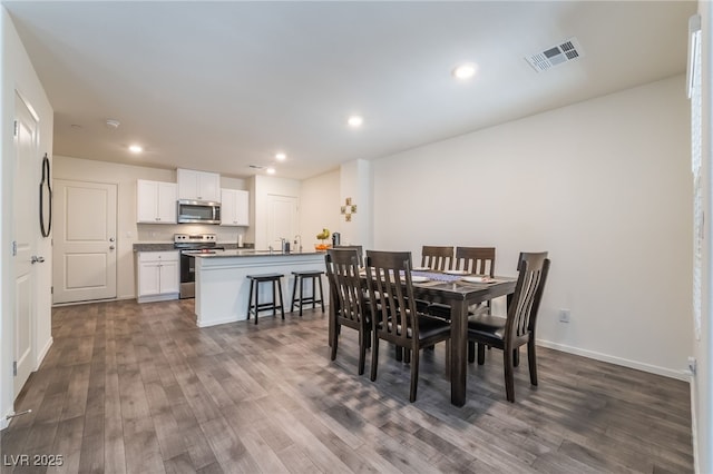 dining space with baseboards, dark wood-type flooring, visible vents, and recessed lighting