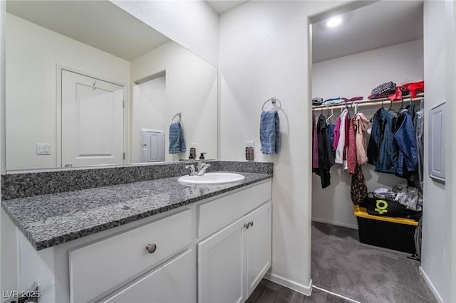 bathroom featuring a spacious closet, baseboards, and vanity