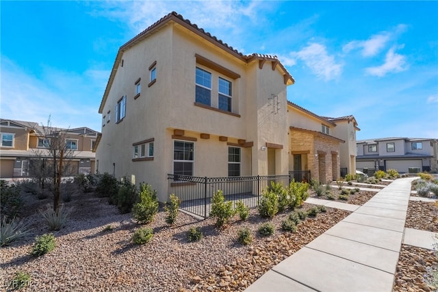 view of side of home with a tiled roof, fence, a residential view, and stucco siding