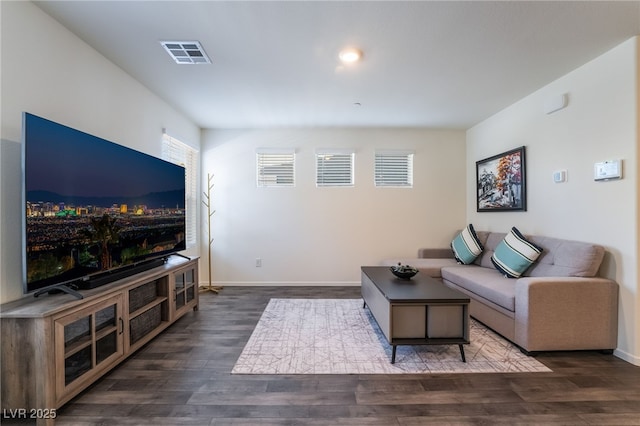 living room featuring dark wood-style flooring, visible vents, and baseboards